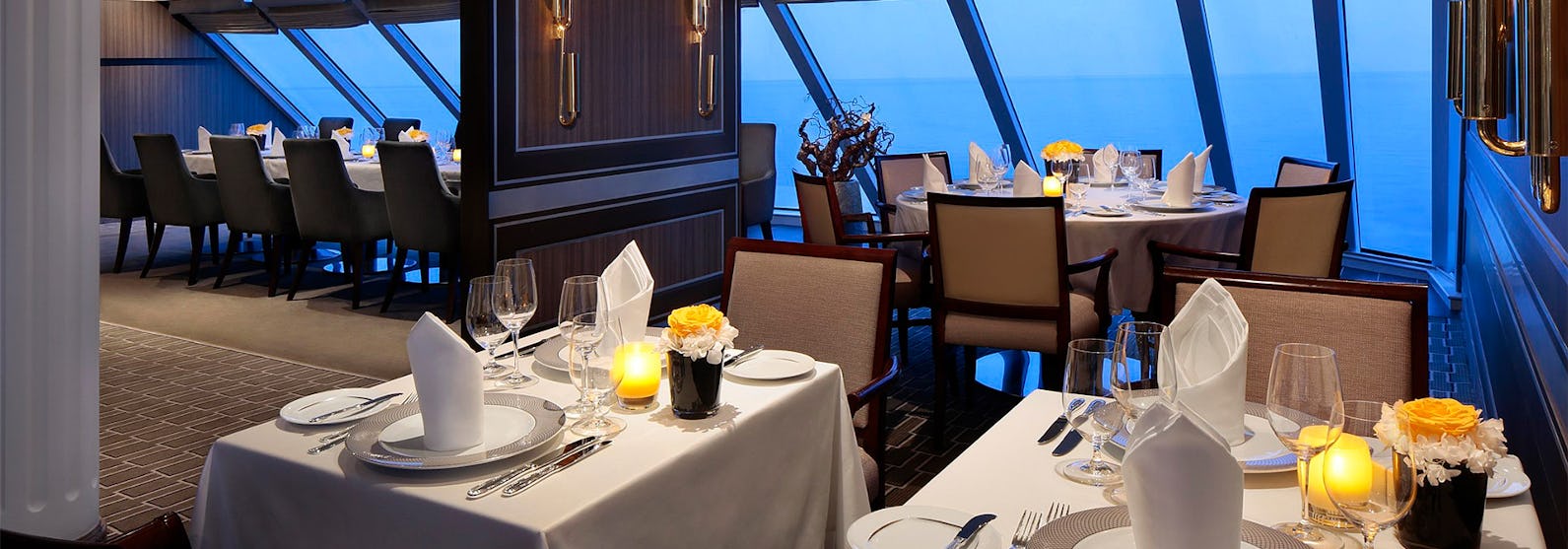 Bild från en av Azamara Quest lyxiga restauranger med stora fönster med utsikt över det blå havet.