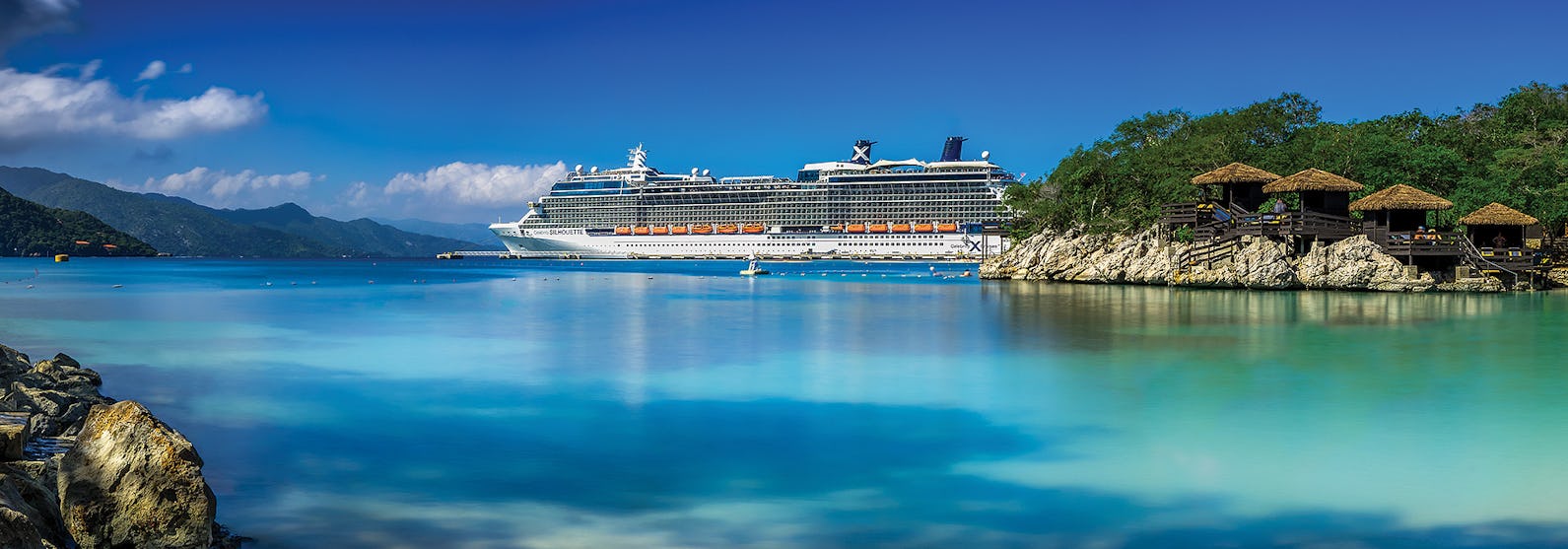 Celebrity Silhouette uppenbarar sig i bakgrunden med ljusblått vatten och en tropisk ö i förgrunden.