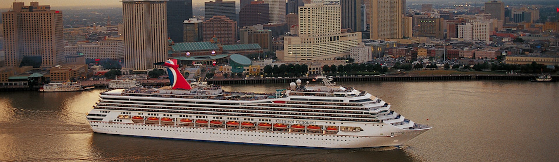 Fartyget Carnival Conquest kryssar fram framför flera skyskrapor.