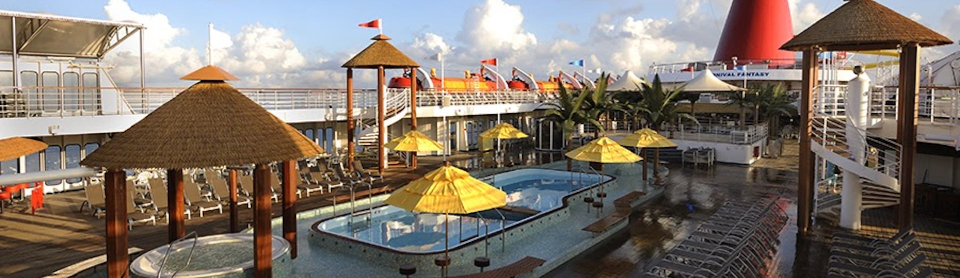 Bild på Carnival Fantasy's sol- och pooldäck med flera solsängar, jacuzzi och en pool.