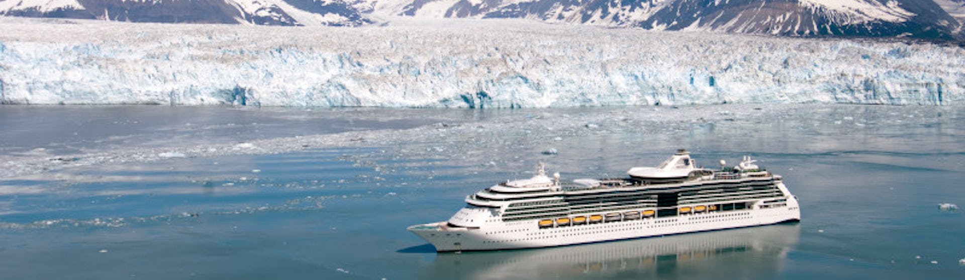 Bild från ovan på Serenade of the Seas som kryssar fram vid snötäckta berg och isberg i Alaska.