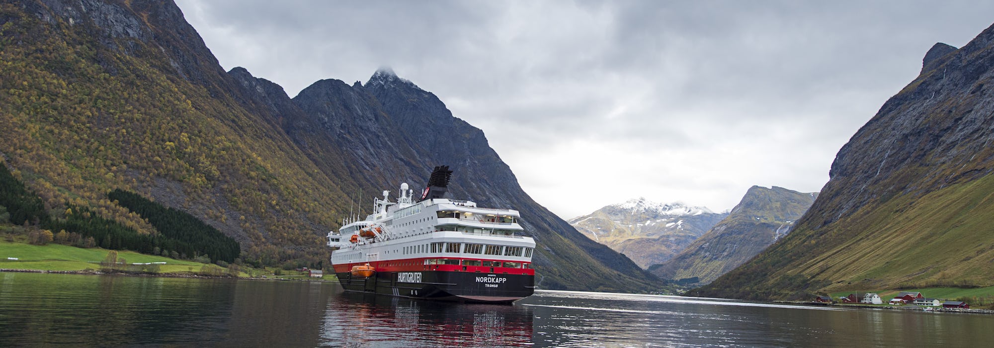 MS Nordkapp glider stilla genom de Norska fjordarna och dess vackra natur med berg runtomkring.