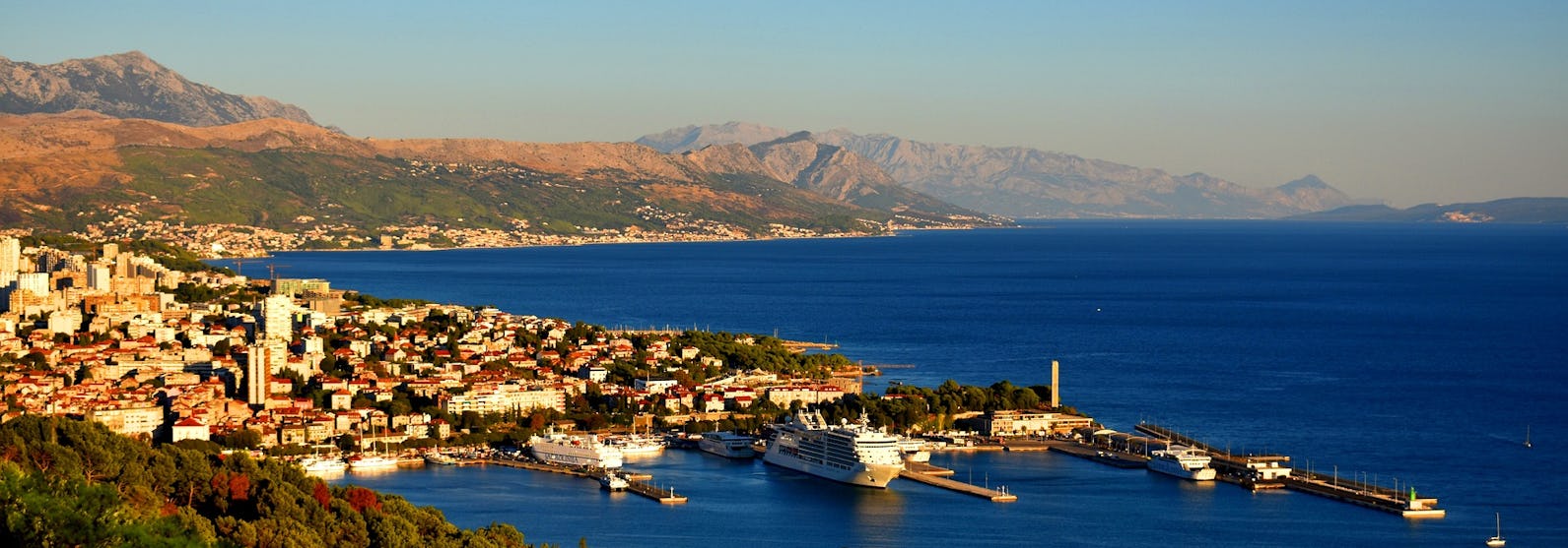 Bild ovanifrån på staden Split's hamn med berg och vatten i bakgrunden.