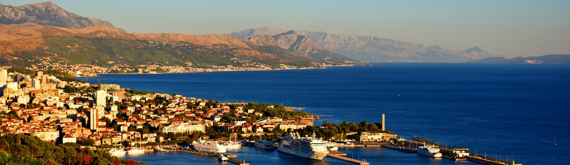 Bild ovanifrån på staden Split's hamn med berg och vatten i bakgrunden.