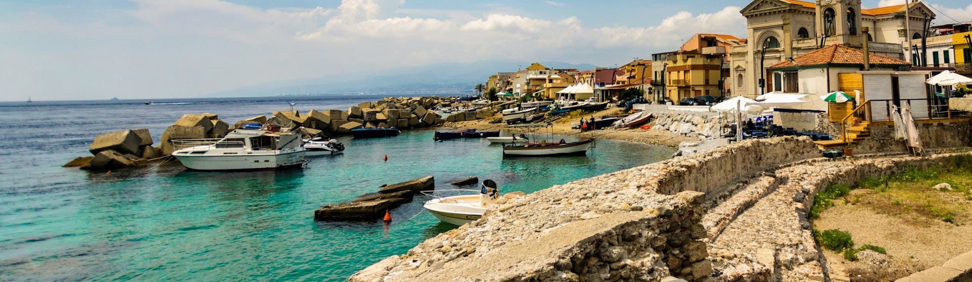 Messina i Italien med havet, små båtar och gamla byggnader.